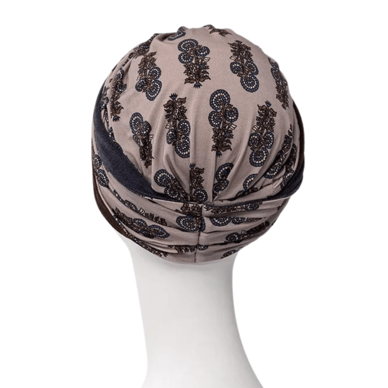 Turbante Shakti beige con patrón paisley oscuro, vista trasera en maniquí con un elegante nudo en la nuca