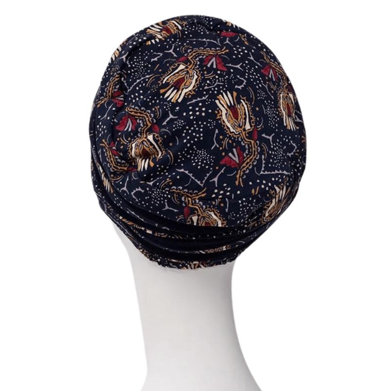 Turbante Shanti con estampado Amber Garden visto desde atrás en maniquí blanco, con el motivo azul oscuro de plumas y tallos