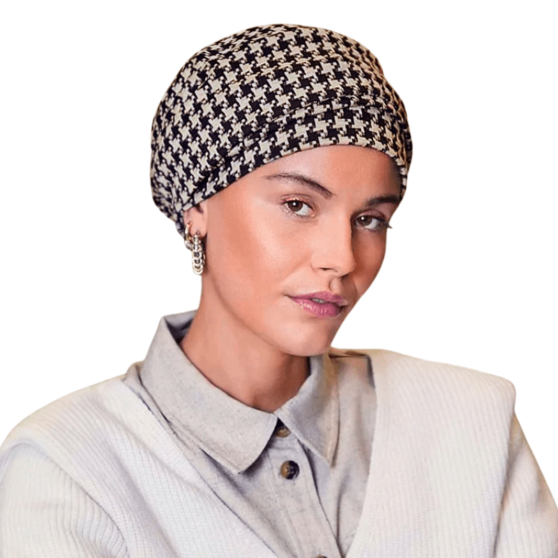 Turbante Lea con estampado de pata de gallo negro y beige, llevado por una mujer de frente, con volumen elegante