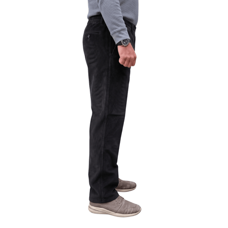 Cómodos pantalones de pana negros con cintura elástica y bolsillos laterales, vistos de lado en una persona