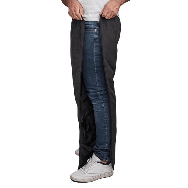 Hombre desabrochando pantalones térmicos Dobsom negros por el lado, sobre vaqueros azules y zapatillas blancas