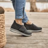Mujer con zapatillas New Feet gris antracita en un suelo de madera, vista lateral de los pies