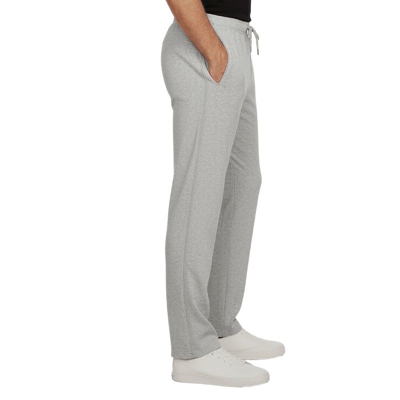 Pantalones de chándal grises con cremalleras laterales cerradas y bolsillos, vistos de lado en una persona